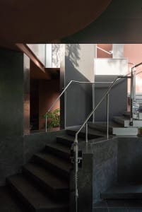 A modern staircase in a residential building with metal stairs and concrete walls, suggesting a functional and stylish design