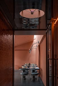 A cozy restaurant dining area with wooden tables, wine glasses, and a warm atmosphere