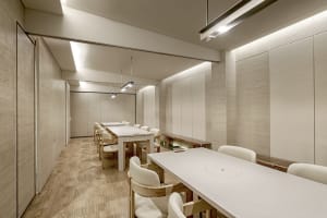 A modern dining area with a large wooden table and white chairs in a clean and modern setting