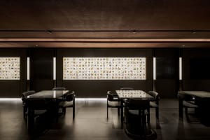 A modern restaurant with glass walls, featuring two dining tables and several chairs, creating an inviting and comfortable atmosphere for guests