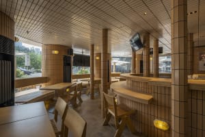 A restaurant interior with wooden tables and chairs, TVs on the walls, and a welcoming atmosphere