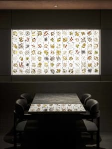 A darkened dining space with a marble table surrounded by chairs, creating an intimate and inviting atmosphere