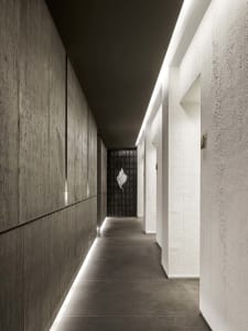A dimly lit hallway in an old building with white walls and floors, featuring two doors on either side
