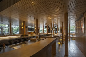 A warm and inviting restaurant kitchen with wooden floors and walls, featuring tables, chairs, and wine glasses, with bottles of condiments and ingredients on surfaces