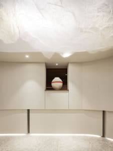 A modern kitchen with two large white cabinets, one on the left and one on the right, with a small vase on top of one of the cabinets, in a warm and well-lit space