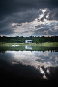 A serene lake surrounded by trees and houses, with a couple in a boat on the water
