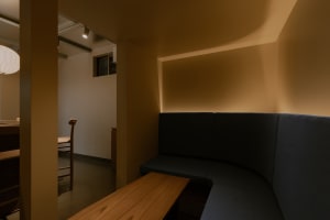 Cozy living and dining space with yellow walls, a window, and natural light, featuring a bench, chair, and inviting atmosphere