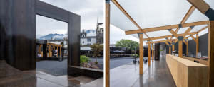 Black building facade with patio and benches, floor plan showing interior rooms and dining table
