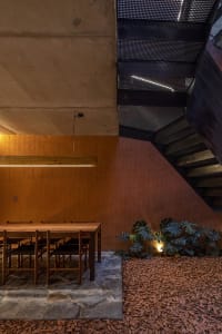 Modern staircase with concrete steps and metal railing, surrounded by a dining table and chairs in a well-lit space