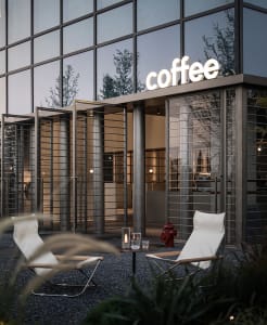 Bright coffee shop with a large glass window, two outdoor chairs, and a fire hydrant in a modern urban setting