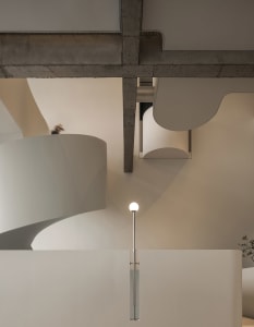 A modern staircase with concrete steps, a lamp, and a dog near the bottom, set in a possibly museum or modern building