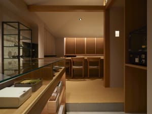 A warm and inviting restaurant kitchen with wooden floors and walls, featuring chairs for staff and dining tables for customers