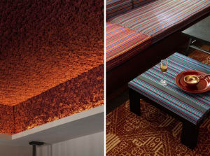 A living room with a striped couch, orange ceiling with a red pattern, and bottles on the couch