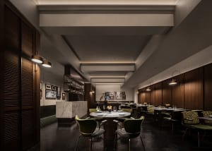 A well-lit dining area with multiple tables and chairs, wine glasses, and a modern interior design