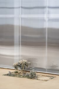 Modern indoor space with a large metal wall, two small potted plants, and a minimalist atmosphere