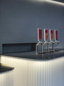 A simple bar area with two red drink dispensers on a marble countertop, creating a stylish and elegant atmosphere