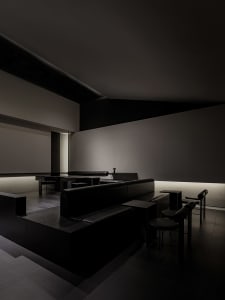 Dark and moody restaurant with black leather seating, grey tones, and a sophisticated ambiance