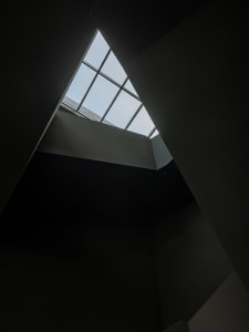 A small, triangular room with a skylight in the ceiling, allowing sunlight to create a bright spot on the wall