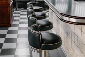 A modern bar with multiple black leather stools and a well-lit counter, creating an inviting atmosphere for customers