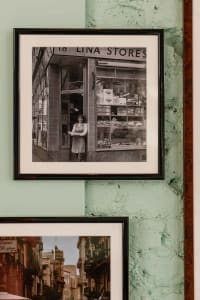 A vintage grocery store facade with a woman standing in front, giving a nostalgic feel