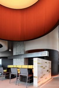 A restaurant dining area with red wood paneling, multiple chairs, and tables, creating a cozy and welcoming atmosphere