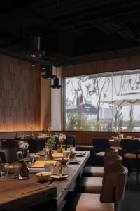 Warm and inviting restaurant interior with wooden floors and walls, featuring dining tables, chairs, and decorative elements