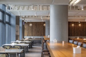 Empty restaurant with wooden floors and walls, featuring chairs around dining tables in a calm and inviting atmosphere