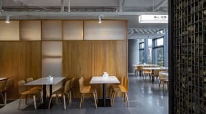 Warm and inviting restaurant interior with wooden walls and flooring, featuring dining tables and chairs under white tablecloths