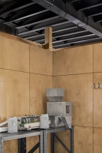 Industrial workspace with a large machine and smaller machines on either side, surrounded by wood panel walls