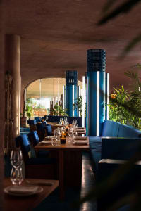 A cozy dining area with a long wooden table, chairs, wine glasses, and candles, situated next to a large wall