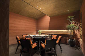 A wooden dining table surrounded by chairs, with cups, bowls, and vases on the table, creating a warm and inviting atmosphere