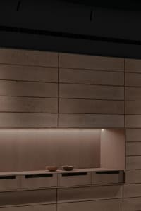 A kitchen with wooden cabinets and countertops, featuring two bowls on the countertop and warm lighting creating a cozy atmosphere