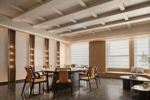 Modern restaurant interior with wooden elements, tables, chairs, and a bar, featuring wine glasses and a sophisticated atmosphere
