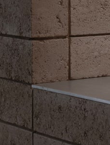 A serene outdoor space with a brick wall and a built-in concrete bench, inviting relaxation and contemplation