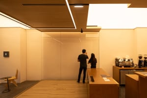 Two people in a modern office with a glass partition, wooden floor, and countertop, creating a warm and professional atmosphere