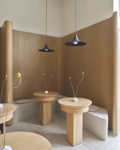 A well-lit room with wooden tables and chairs, white vases, and a warm atmosphere