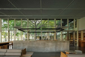 Modern room with a concrete wall, wooden table, and two chairs, with sunlight entering through a large window