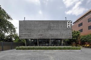 Modern building with a large gray concrete wall featuring windows with curtains, set against a bright daylight background