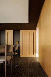 Empty restaurant with wooden walls and floors, featuring dining tables and chairs in a clean and well-organized atmosphere