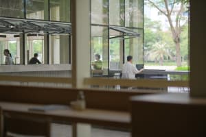 A modern dining space with glass walls, natural light, and a relaxed atmosphere, featuring three chairs and two dining tables