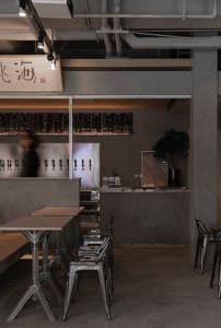 A modern Asian restaurant with a bar area and dining tables, featuring bottles and an inviting atmosphere