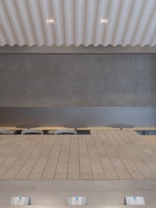 A calm and inviting restaurant with a long wooden dining table surrounded by white chairs and a bench