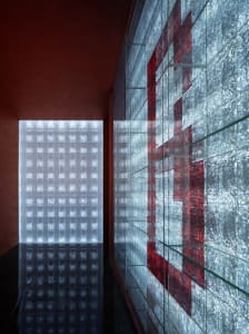 A well-lit hallway with a red accent wall, glass door, and multiple framed pictures on the walls