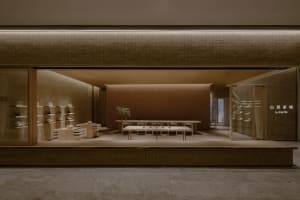 An empty retail space with a large window display, chairs, and potted plants, giving a clean and organized atmosphere
