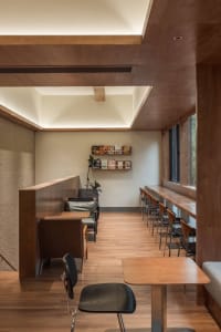 Warm and inviting restaurant interior with wooden floors and walls, featuring comfortable seating areas and scattered books