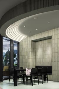 A modern restaurant dining area with a table surrounded by chairs, featuring a combination of black and white elements and warm lighting