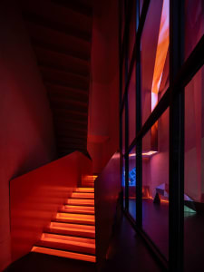 A modern staircase with a red carpet in a well-lit art gallery or museum setting