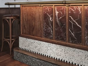Kitchen with a wooden countertop, marble backsplash, and a chair for seating, set against a neutral background