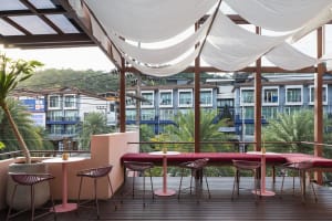Inviting outdoor dining space with a pink table and multiple chairs, surrounded by a comfortable ambiance