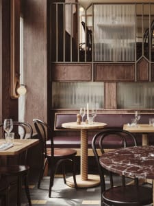 Cozy restaurant interior with wooden floors and walls, dining tables, chairs, and wine glasses
